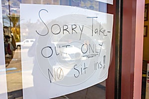 Handwritten sign at restaurant stating Sorry Take-Out Only No Sit Ins due to coronavirus pandemic photo