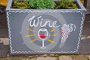 Handwritten sign wine and simple drawing of a wineglass with red wine and blue grapes. Original advertisements attracting people