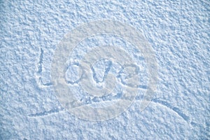 Handwritten underlined word `Love` is written on fluffy snow, on a frosty winter evening. Valentine`s Day.