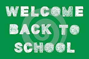 Handwritten white bold chalk lettering welcome back to school text on green background
