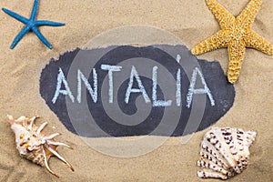 Handwritten word ANTALIA written in chalk, among seashells and starfishes photo