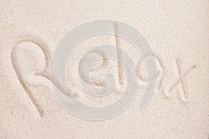 Handwritting word RELAX in sand above view macro