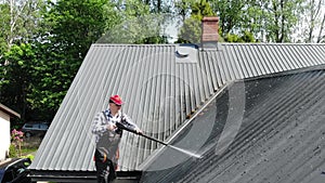 Handy man washing roof with high pressure