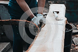 Handy woodcutter prepares larch wood for later processing. Planing wood. Working larch boards with traditional tools. Hand