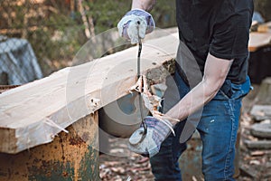 Handy woodcutter prepares larch wood for later processing. Planing wood. Working larch boards with traditional tools. Hand