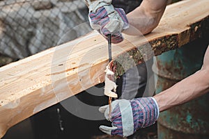 Handy woodcutter prepares larch wood for later processing. Planing wood. Working larch boards with traditional tools. Hand