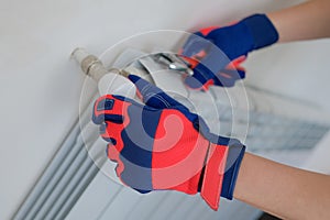 Handyman adjusting temperature of heating battery at home.