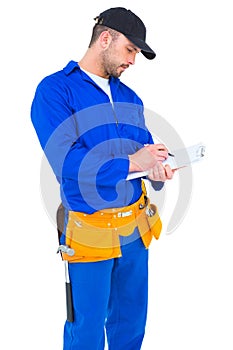 Handyman in blue overall writing on clipboard