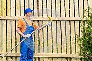 Handyman in blue working uniform checks the condition of paint roller