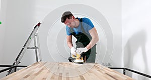 Handyman carpenter sanding wooden table in workshop