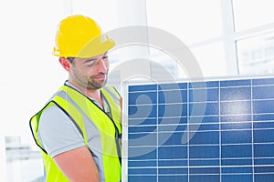 Handyman carrying solar panel at office