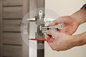 Handyman changing core of door lock indoors, closeup. Space for text