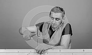 Handyman concept. Man, handyman in working uniform and protective gloves handcrafting with hammer, light blue background