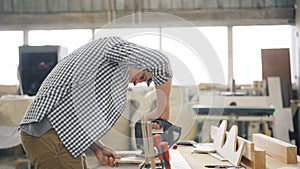 Handyman cutting wood with fretsaw using electric instrument in workshop