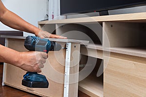 Handyman fixing over tight drawer slides of TV shelf. Concept Fix stuck wooden drawer slides