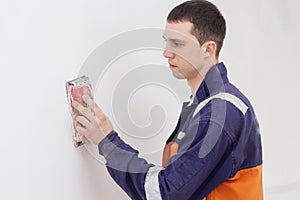 Handyman grinding wall with sandpaper