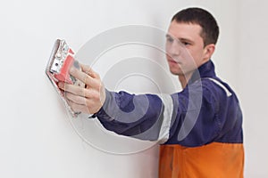Handyman grinding wall with sandpaper