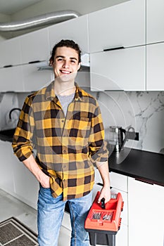 Handyman holding tools standing in kitchen. Professional plumbing services