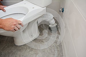 Handyman installing flush toilet. Repairing, dismantling toilet bowl in the bathroom