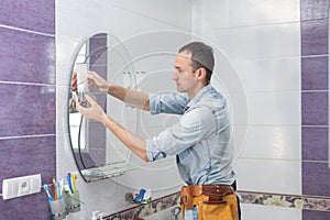 Handyman installing a mirror in bathroom.