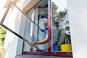 Handyman installing mosquito net mesh screen on house window