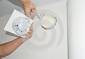 Handyman installing new bath vent fan, ventilation system in the house bathroom . Bath fan repair, installation