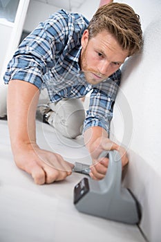 Handyman laying down carpet in new house