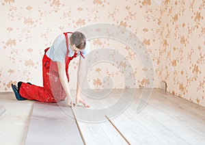 Handyman laying down laminate flooring boards