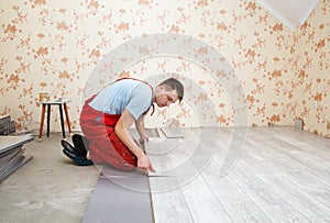 Handyman laying down laminate flooring boards