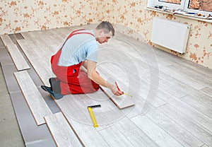 Handyman laying down laminate flooring boards