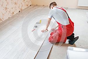 Handyman laying down laminate flooring boards photo