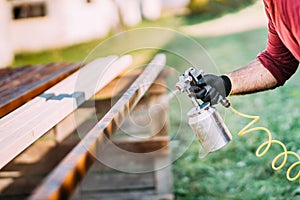 Handyman, male construction worker painting with spray gun on site