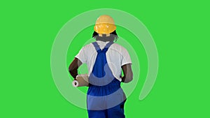Handyman man in protective helmet hold wallpaper rolls walking and pointing with a brush to the sides on a Green Screen