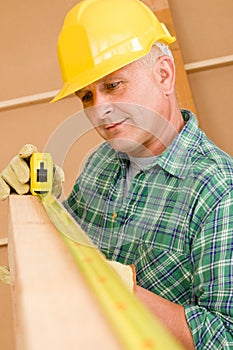 Handyman mature carpenter measure wooden beam