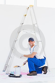 Handyman in overalls opening paint can at home