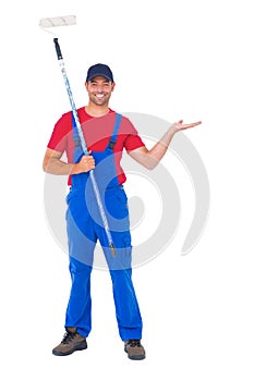 Handyman with paint roller presenting in his palm on white background