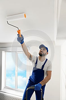 Handyman painting ceiling with white dye