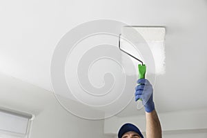 Handyman painting ceiling with white dye, closeup. Space for text