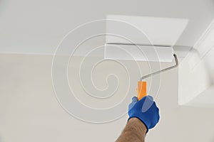 Handyman painting ceiling with white dye, closeup. Space for text