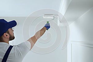 Handyman painting ceiling with white dye indoors, back view. Space for text