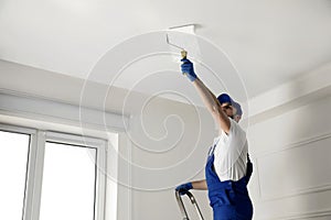 Handyman painting ceiling with white dye, space for text