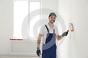 Handyman painting wall with roller brush indoors. Professional construction tools