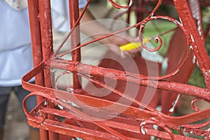A handyman paints old glider swing made of wrought iron with red oxide primer paint. Restoring or rebuilding outdoor furniture or