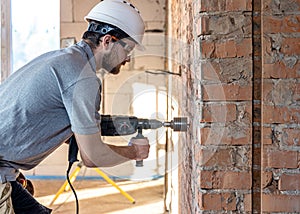 Handyman in the process of drilling a wall with a perforator