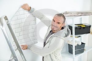 handyman putting up wallpaper on white walls