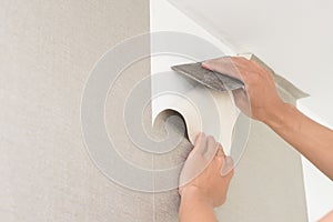 Handyman putting up wallpaper on the white walls