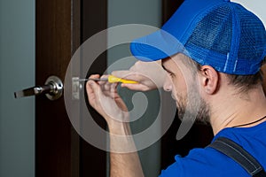 Handyman repair the door lock in the room. Closeup of man repairing the doorknob.