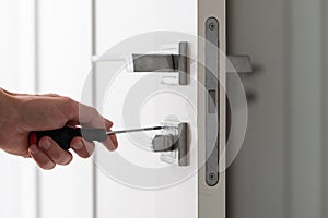 A handyman repair the door lock in the room. The concept repair yourself. Selective focus