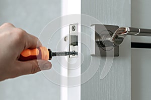 Handyman repair the door lock in the room. The concept repair yourself. Selective focus.