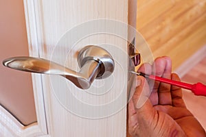 Handyman repair the door lock in the room, Man fixing lock with screwdriver, Close-up of repairing door, professional locksmith